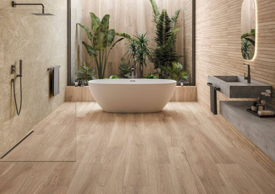 SEASON-CARAMEL-OAK-WOOD-EFFECT-PORCELAIN-TILES. Image shows caramel oak wood effect porcelain tiles in bathroom with bathtub and foliage in background