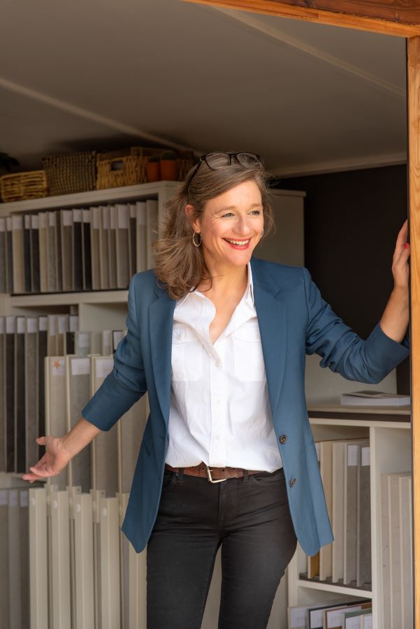 SHOWROOM. Image shows lady at door of a tile showroom smiling and welcoming in customers