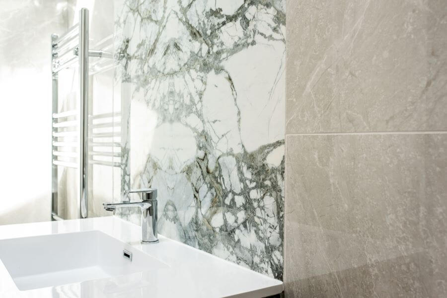 HAVEN-STONE-BATHROOM. Image shows marble effect centre piece above sink on wall with porcelain stone effect tiles around it.