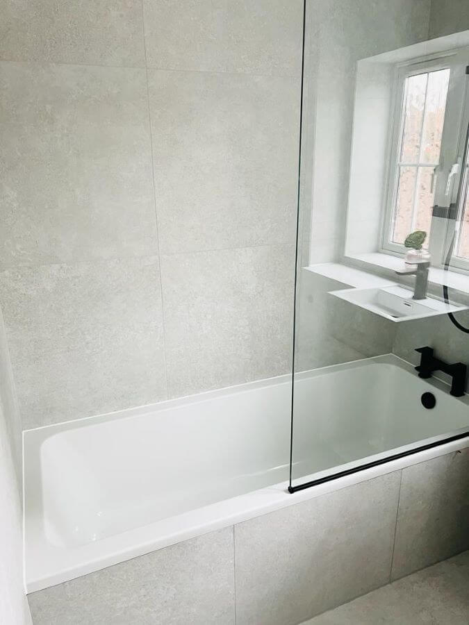 DOCKLANDS-WHITE. Image shows white concrete effect ties on floor of bathroom, to side of bath and on the walls