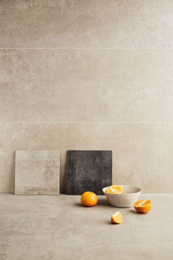 Beat beige cement look porcelain tile. Image shows close up of beige tiles with small anthracite sample and some oranges