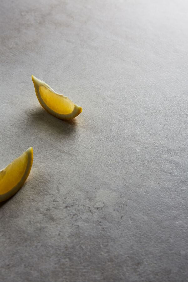 BEAT-GREY-CEMENT-LOOK-PORCELAIN-TILE-CLOSEUP. Image shows close up of tile with lemons on surface