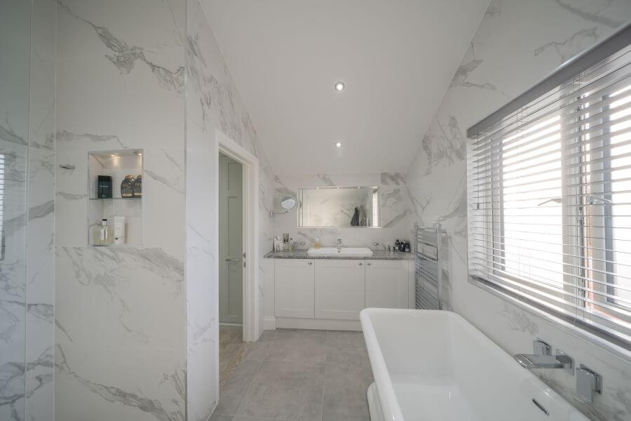 WILLOWS-2. Image shows bathroom with carerra marble porcelain tiles to walls and grey floor tile with bath and sink unit