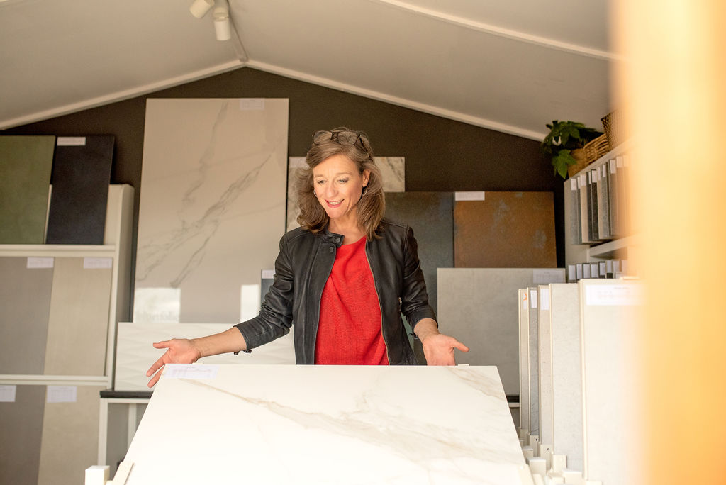 JO-IN-SHOWROOM. Image shows lady in red jumper showcasing a tile on a stand