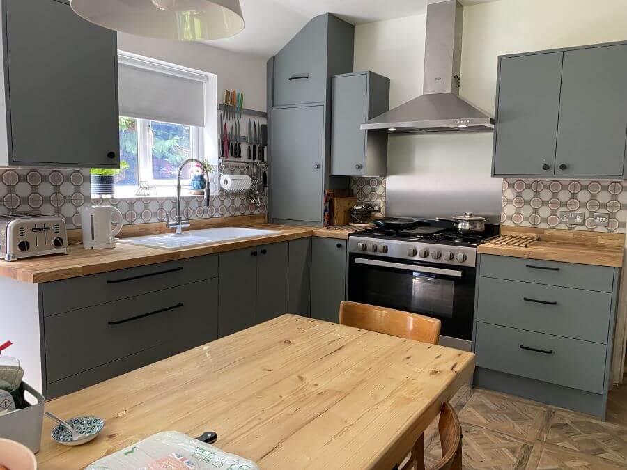 TANGLE-TILES. Image shows green-grey kitchen with wooden versailles style floor tiles and pink feature tiles to walls