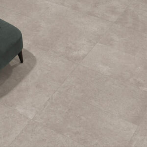 ARTISAN-GREY-CONCRETE-LOOKING-TILES-FLOOR. Image shows grey concrete looking tiles on a floor with a turquoise footstool