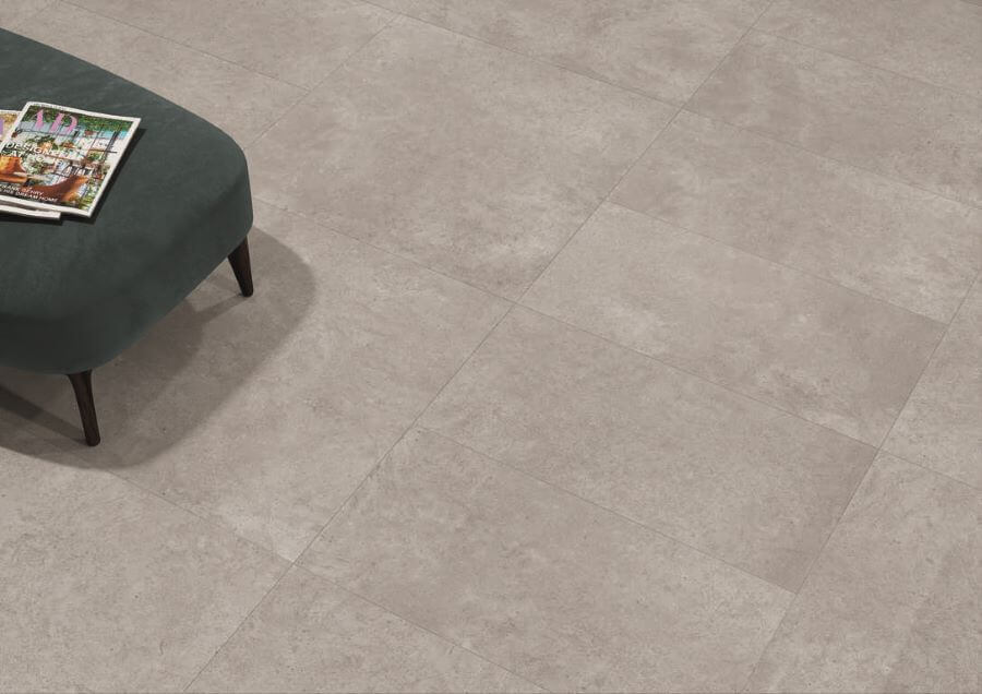 Artisan Grey. Image shows grey concrete looking tiles on a floor with a turquoise footstool