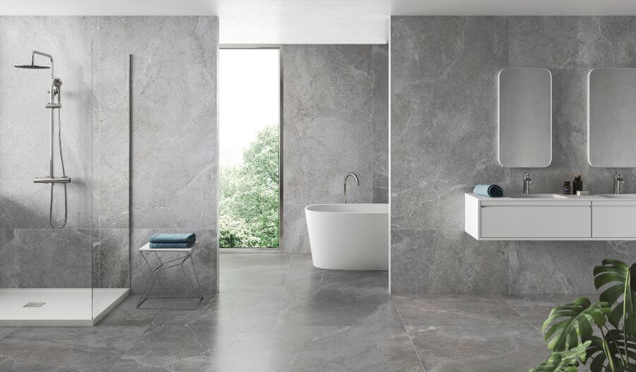 Bliss Grey. Image shows grey porcelain large stone tiles on bathroom wall and floors with shower, bath and vanity unit