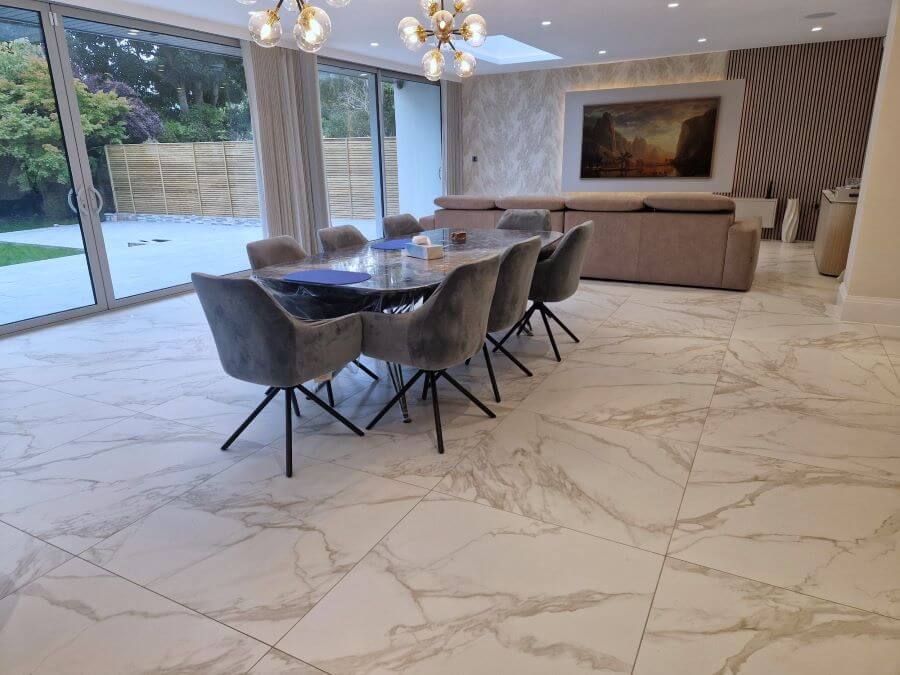 CARERRA-ORO-MARBLE-TILE-LOUNGE. Image shows gold veined marble porcelain tile in lounge with table and chairs