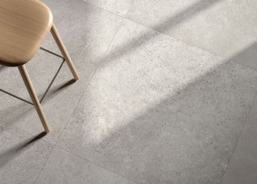 Chic silver. Image shows close up of silver limestone look porcelain tile in a kitchen with a wooden stool