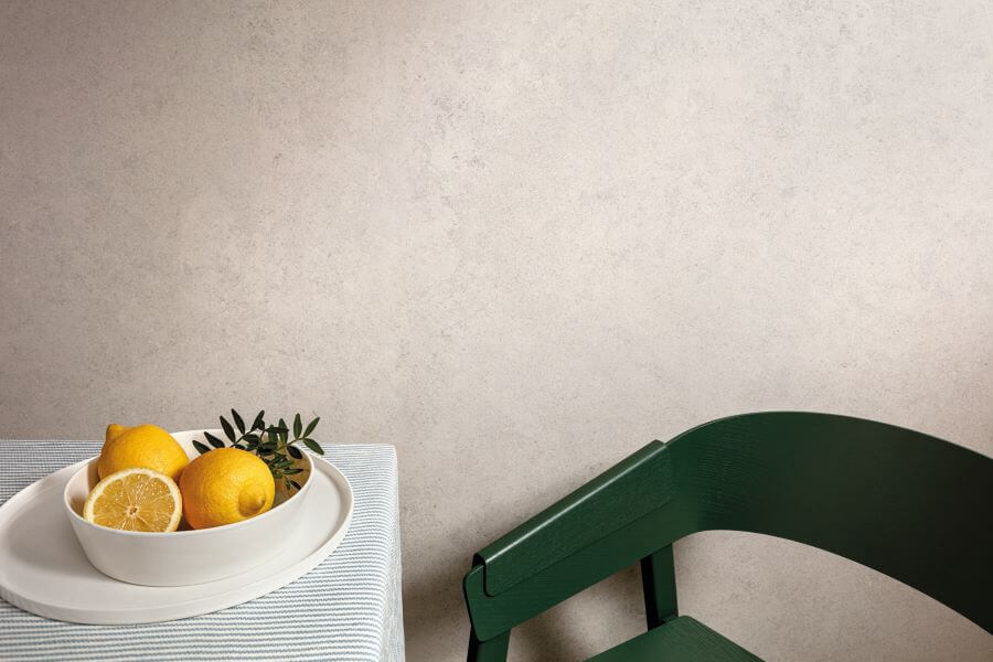 CHIC-WHITE-LIMESTONE-LOOK-PORCELAIN-TILE. Image shows white limestone look porcelain tile to wall with green chair and table with lemons