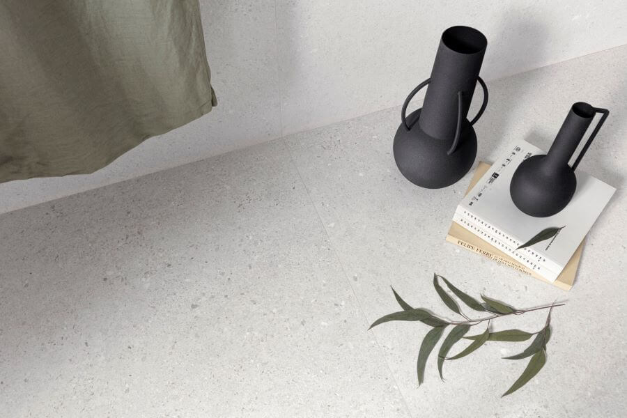 Define White. Image shows white terrazzo effect porcelain tile close up with flasks and books