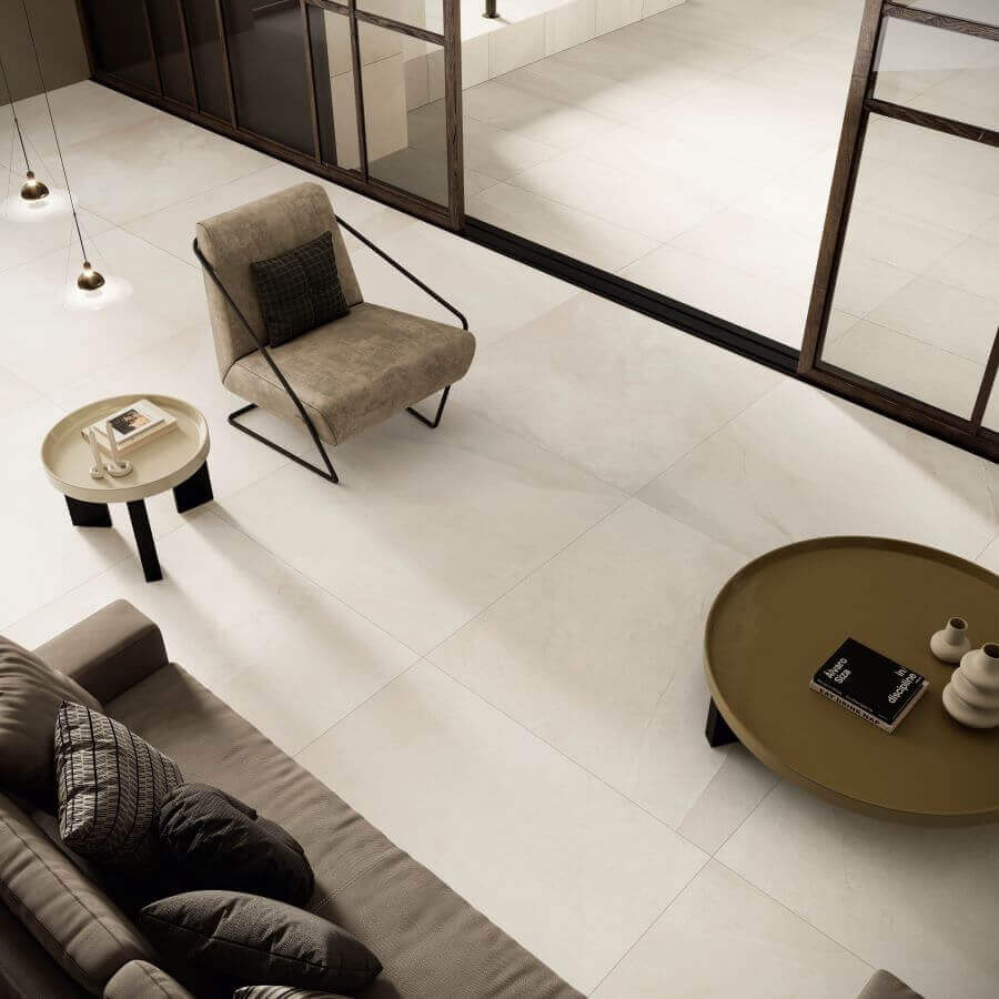 Ethos Shore. Image shows cream stone look porcelain tile in a lounge with a sofa, chair and table