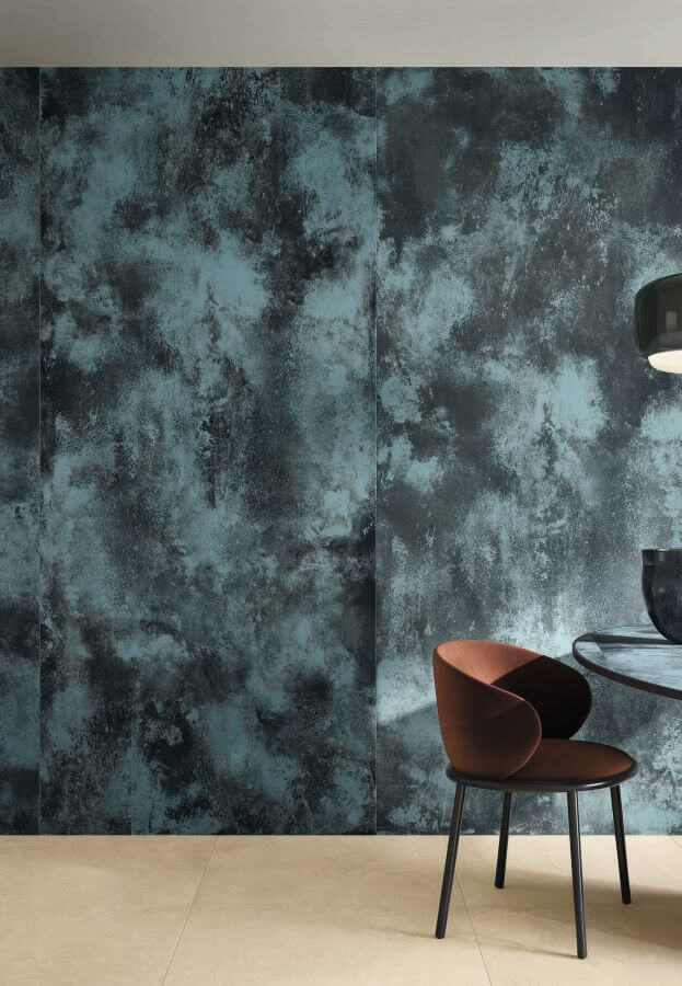 FORGE-BLUE-MOTTLE-PORCELAIN-METALLIC-TILES-WALL. Image shows blue metallic tiles to wall with brown chair in front