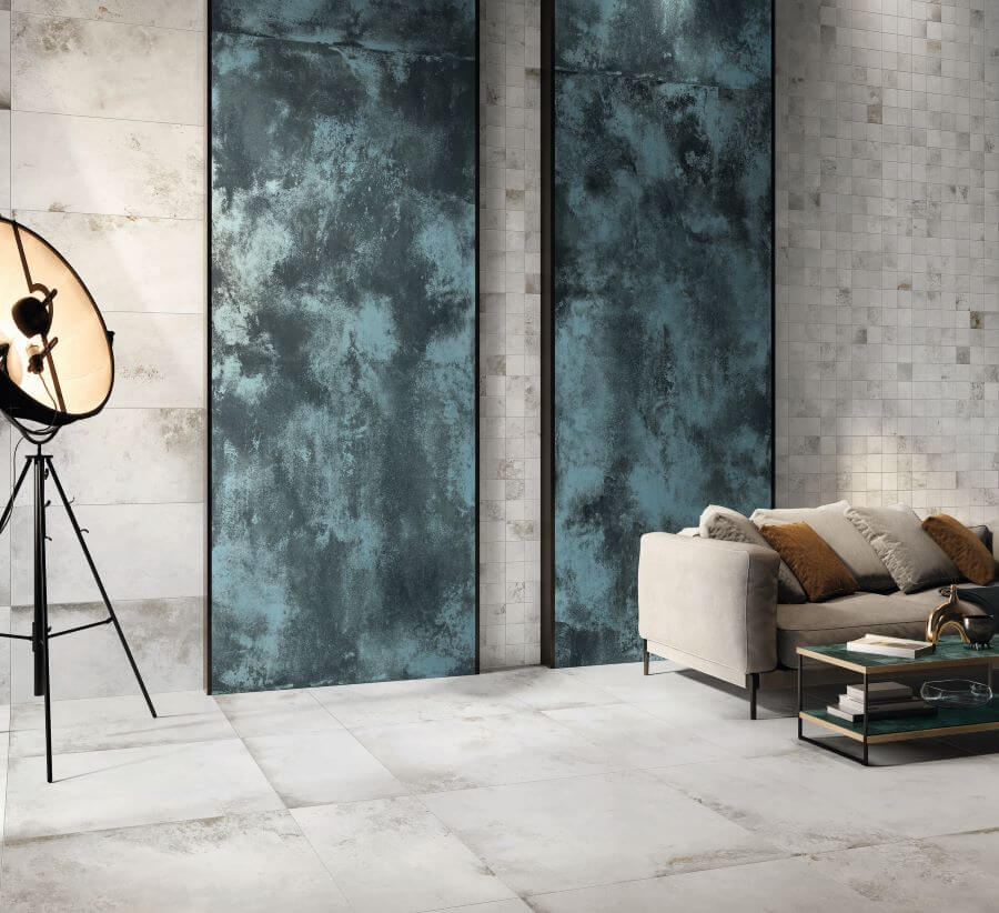 FORGE-BLUE-MOTTLE-PORCELAIN-METALLIC-TILES. Image shows blue metallic tiles in panels on a wall with a lamp and sofa