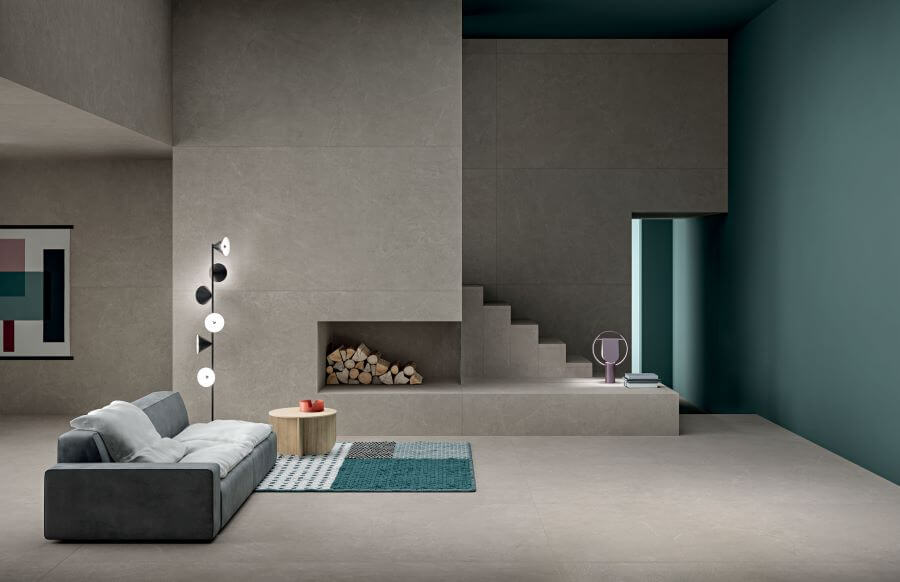 POISE-GREIGE-STONE-LOOK-PORCELAIN-TILES. Image shows grey-beige stone look porcelain tiles in open plan living area with grey sofa and aqua mat