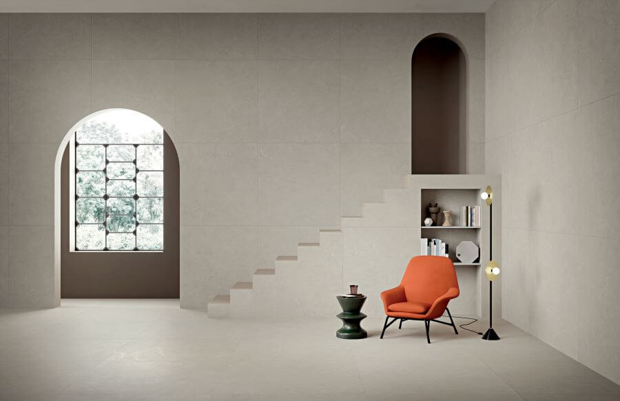 POISE-PEBBLE-STONE-LOOK-PORCELAIN-TILES. Image shows pebble stone look porcelain tiles in open plan lounge with orange chair and steps