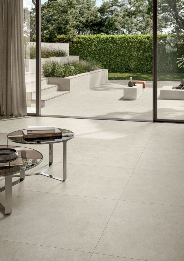 POISE-PEBBLE-STONE-LOOK-PORCELAIN-TILES. Image shows pebble stone look porcelain tiles in a lounge with co-ordinating tiles on patio