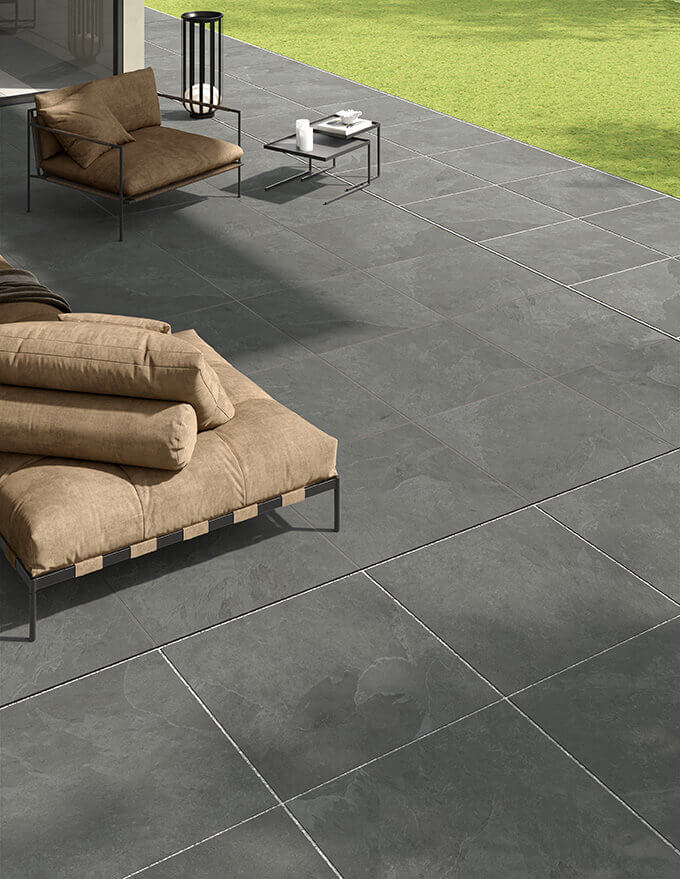 ASPECT-CHARCOAL-PORCELAIN-TILE-THAT-LOOKS-LIKE-SLATE. Image shows charcoal porcelain tile that looks like slate on patio with lounge furniture