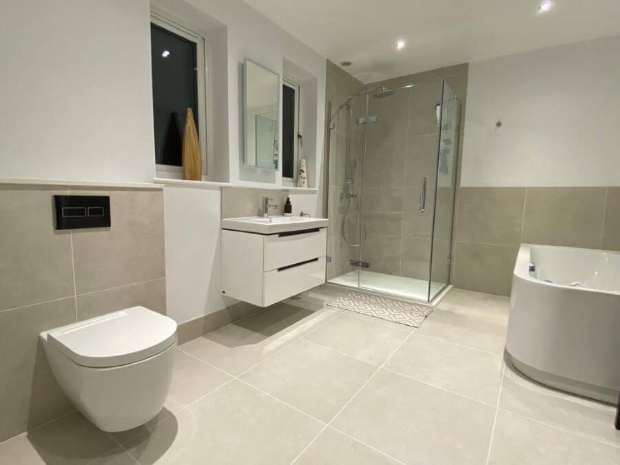 METRO-BONE-600X600-BATHROOM. Image shows light cream porcelain tile on bathroom floor and walls with white sanitaryware