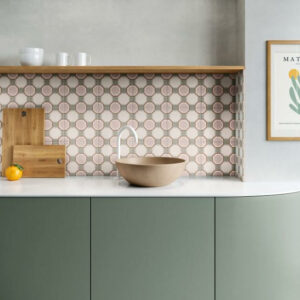 MOTIF-PATTERNED-WALL-TILE-PINK-GEO. Image shows pink and grey patterned wall tile as a kitchen splashback with sage green cabinerty