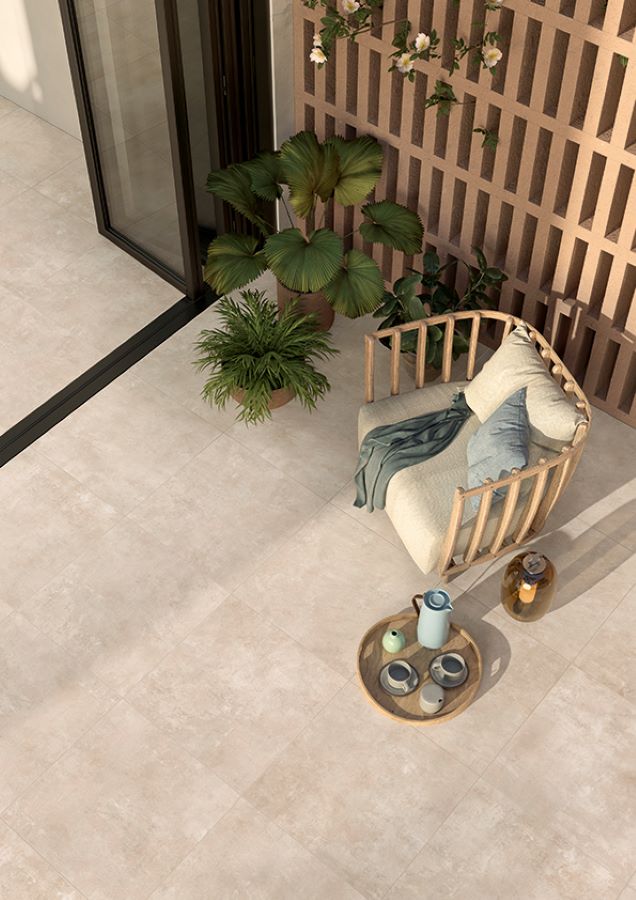 Image shows Minima concrete look tile in Sand on patio with chair and tray with cups