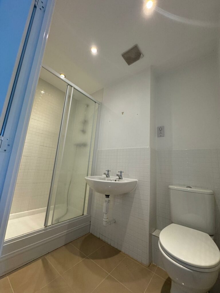 Image shows old bathroom with white sink and toilet